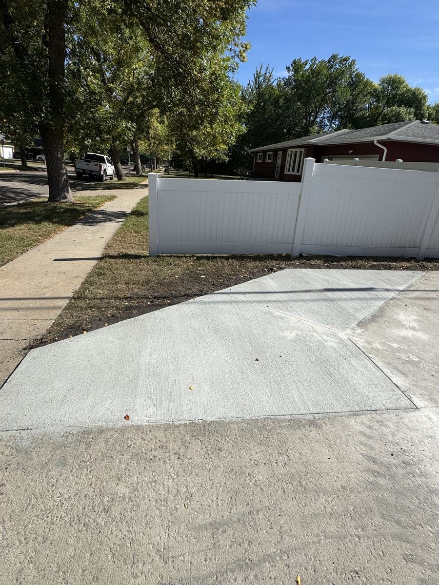 Wide concrete driveway along a privacy fence