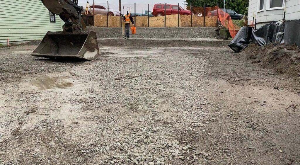 Excavator on a graded, compacted gravel pad ready for the next phase