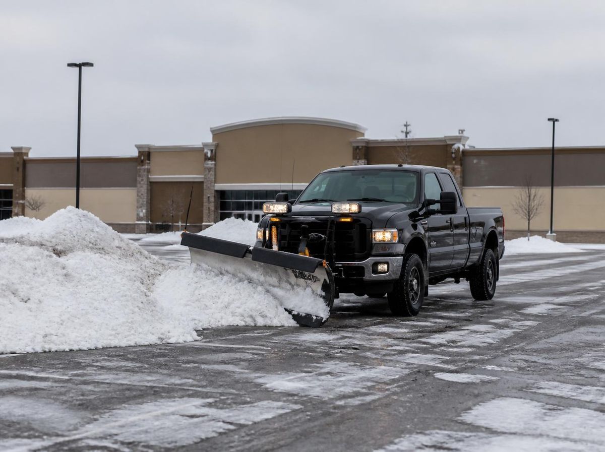 Truck plowing and stacking snow in a commercial parking lot